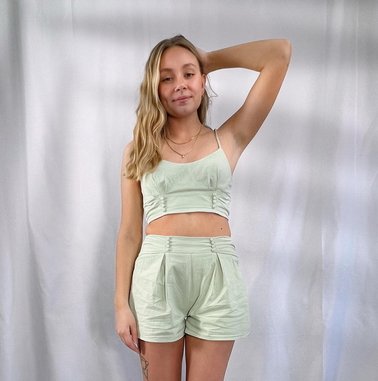 sage green 100% cotton crop top features spaghetti tie strap, sweet heart neck line, pleated detail, cover button, smocking back with exposed metal zipper access
