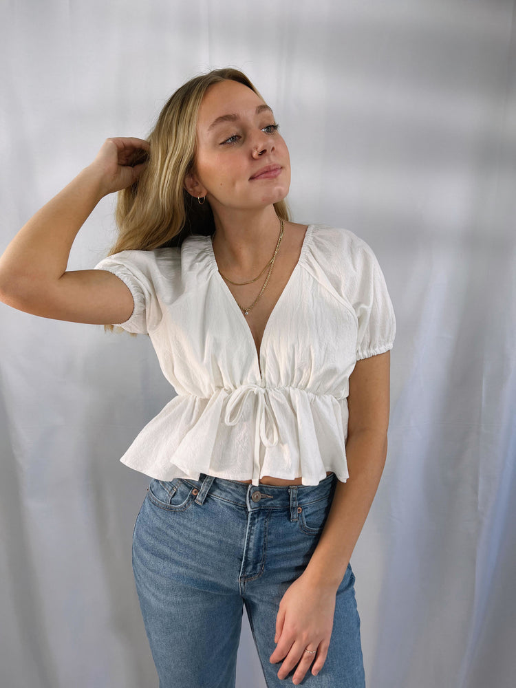 lightweight woven wide v-neckline top with tie detail puff short sleeves elastic shoulders cuffs a ruffled cropped hem open back