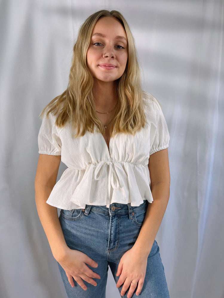 lightweight woven wide v-neckline top with tie detail puff short sleeves elastic shoulders cuffs a ruffled cropped hem open back