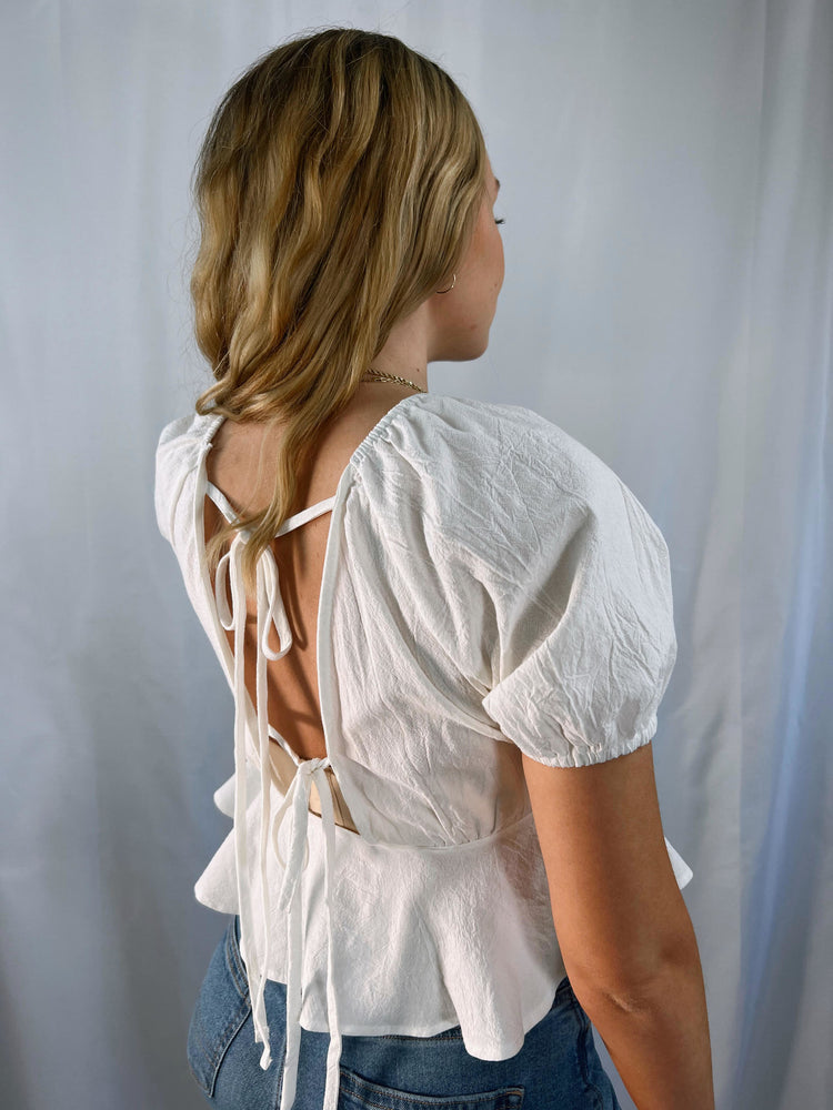lightweight woven wide v-neckline top with tie detail puff short sleeves elastic shoulders cuffs a ruffled cropped hem open back